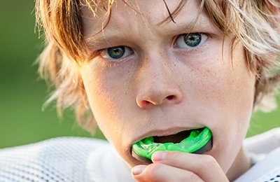 boy putting in green mouthguard