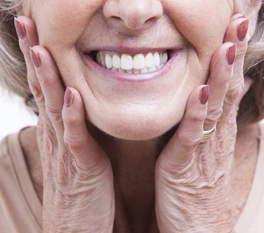 close up of older woman smiling with implant-retained dentures in Brownstown 