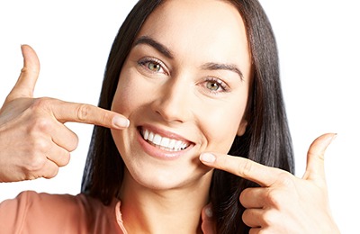 Woman with veneers pointing to her teeth.